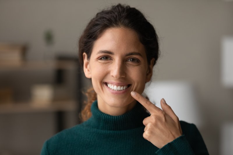 A happy woman pointing to her smile